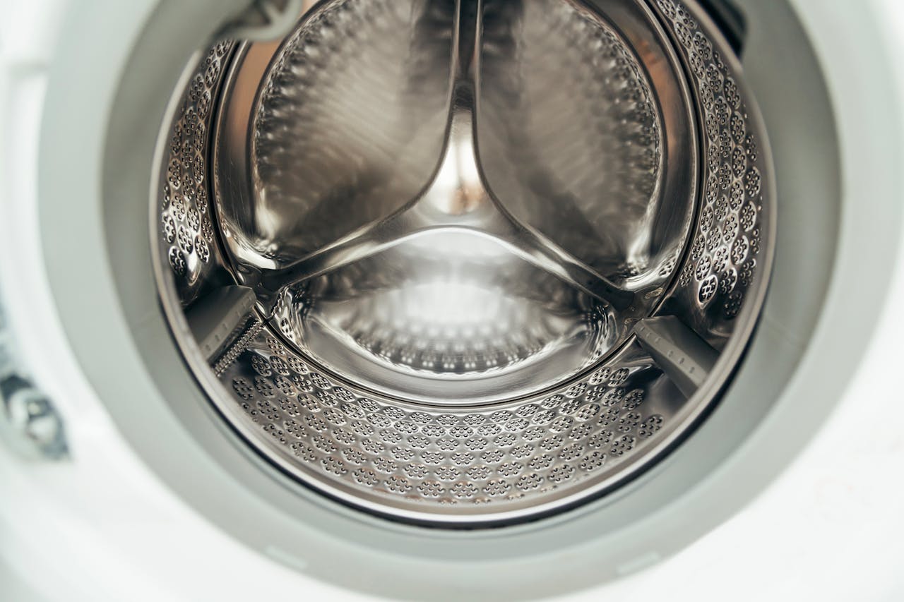services-02 Detailed view of a clean, modern washing machine drum, showcasing shiny stainless steel interior.