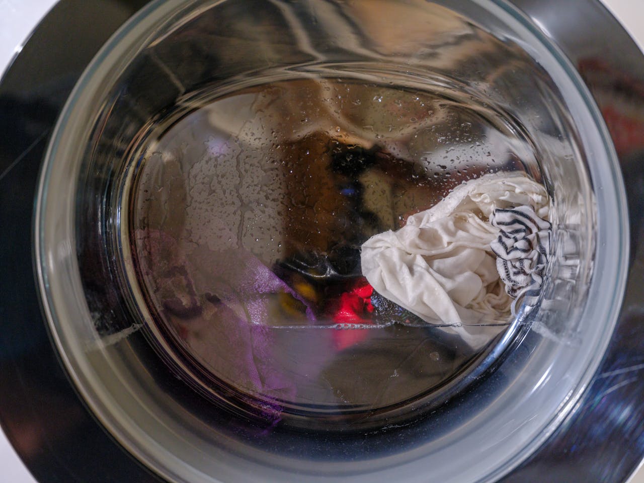 services-03 A clear view of wet clothes spinning inside a front-loading washing machine.