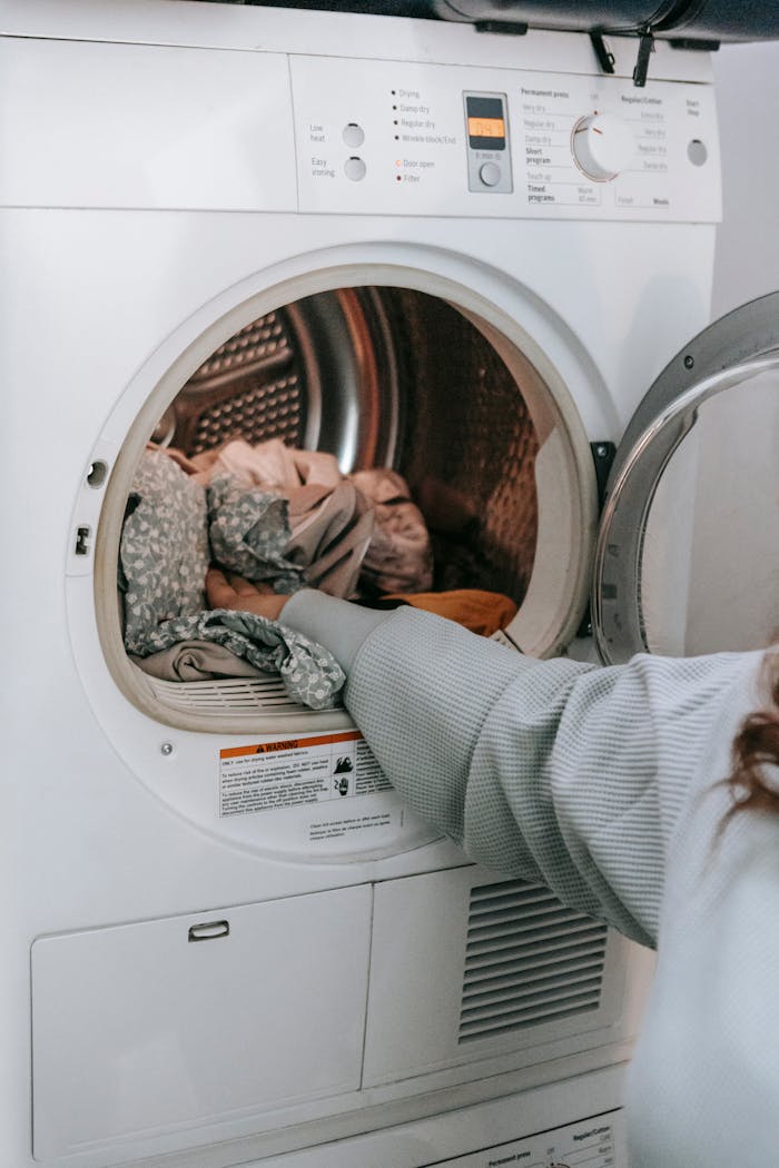 gallery-6 Crop unrecognizable female loading various dirty clothes in modern white washing machine during laundry routine in light room at home