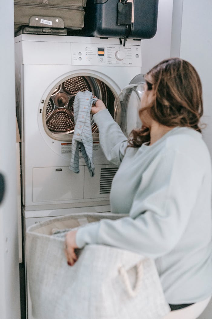 hero-img-02 A woman handling laundry in a home laundry room setting.