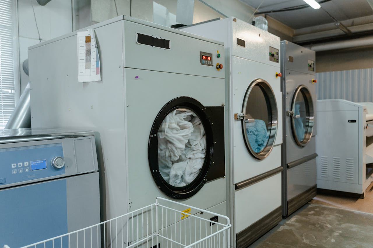 about-01 Interior view of industrial laundry machines in a facility with linens being washed.